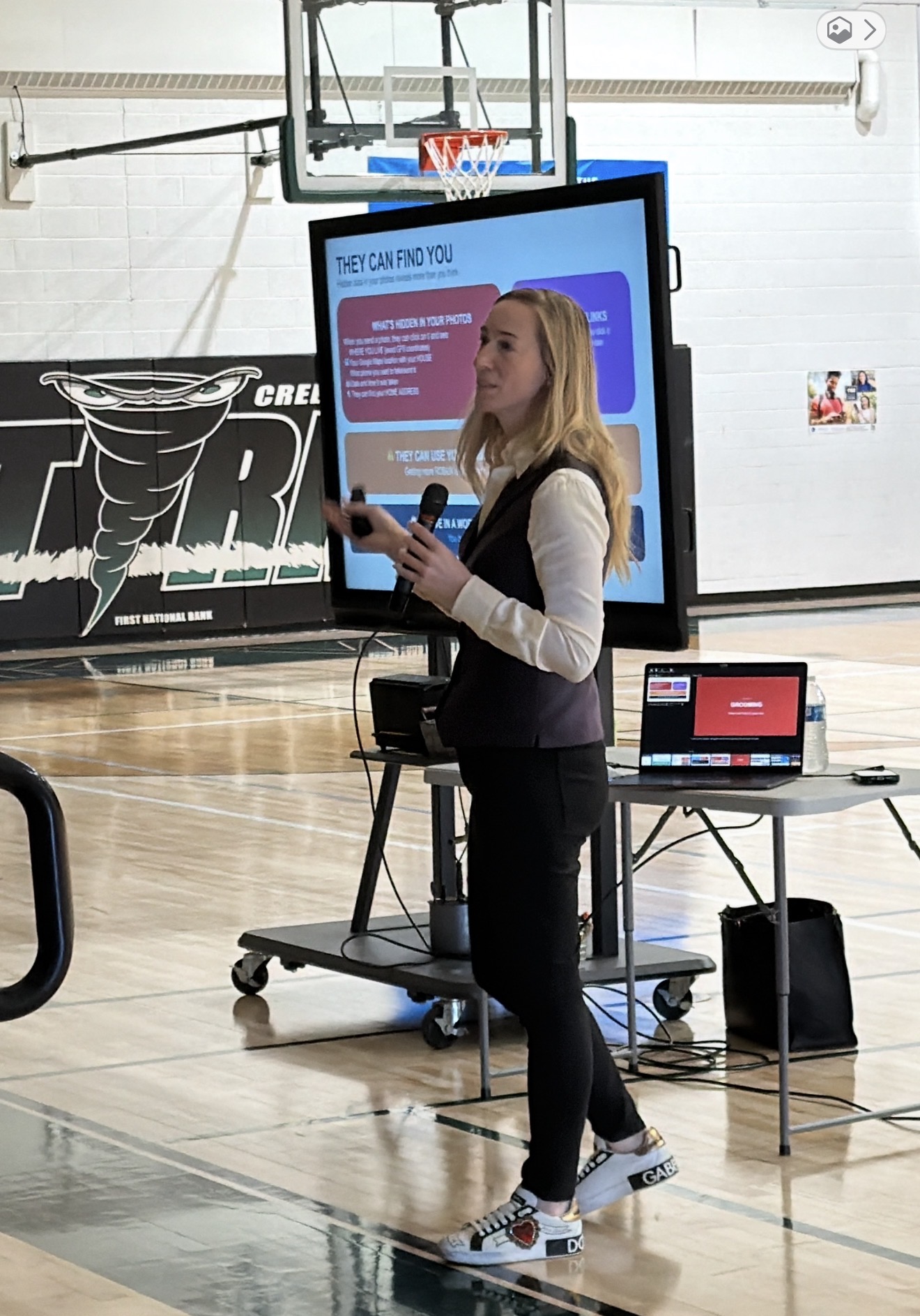 Rachel Fischer — Digital Safety Training Rachel Fischer teaching digital safety in a school gymnasium with a presentation about online privacy and grooming risks